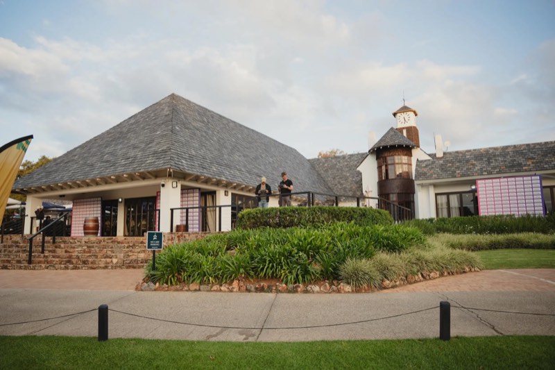 Two drone operators with controllers on the terrace in front of the Royal Johannesburg clubhouse