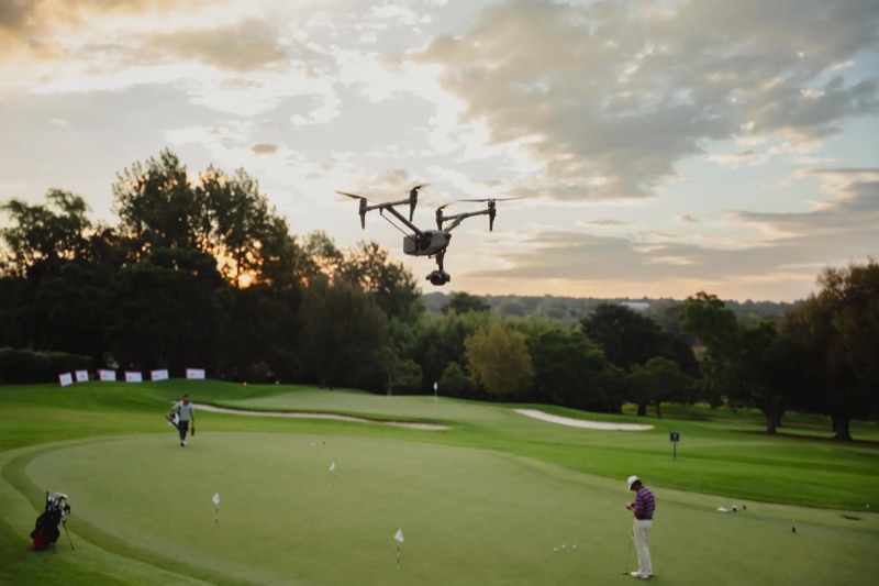 DJI Inspire 3 in flight over a green at Royal Johannesburg Golf Club at sunset, with golfers below