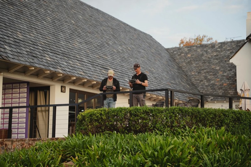 Pilot and camera operator, each with a controller, flying from the clubhouse terrace at Royal Johannesburg Golf Club